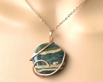May include: A gold chain necklace with a green and white stone pendant wrapped in gold wire.