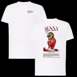 Könnte beinhalten: Weißes T-Shirt mit einem Design, das Ayrton Senna gewidmet ist. Auf der Vorderseite befindet sich das Senna-Logo in roter Schrift. Auf der Rückseite sind ein Porträt von Senna in seinem Rennanzug, ein Rennwagen und Text abgebildet. Das T-Shirt hat einen klassischen Rundhalsausschnitt.