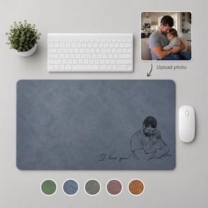 May include: A blue rectangular mouse mat featuring a sketch of a father and child, with the text "I love you!". A white keyboard, mouse, and a small potted plant are also visible.