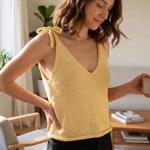 Może przedstawiać: Biały ceramiczny kubek z czarnym uchwytem i napisem "But First, Coffee" czarną, pogrubioną czcionką. Kubek stoi na drewnianej powierzchni.