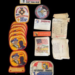 May include: A collection of vintage Boy Scout Jamboree patches, including a 1981 BSA-Navy patch, a 1961 National Scout Jamboree patch, and a 1981 Virginia National Scout Jamboree patch. There is also a can of sardines, a card with the text "jamboree" and a card with the text "1981 National Scout Jamboree Subcamp Flags".