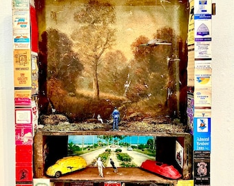 May include: A vintage-style diorama with a miniature scene of a road with palm trees, two cars, and a figure walking. The diorama is made of wood and decorated with matchbox labels and other ephemera. The scene is set against a backdrop of a painting of a forest.