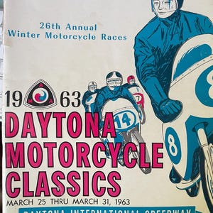 May include: Vintage Daytona Motorcycle Classics souvenir program from 1963. The cover features illustrations of racers in blue suits and helmets on motorcycles, with the event title in pink and white. The program is for the Daytona International Speedway.