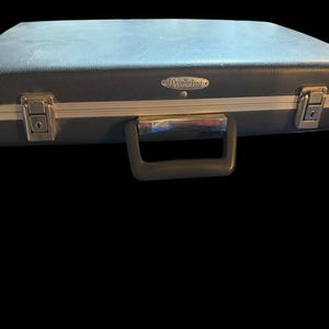 Op de afbeelding: Een vintage blauwe koffer met zilverkleurige afwerking en hardware. De koffer heeft een handvat en twee sluitingen. De merknaam "Overniter" staat op de voorkant van de koffer.