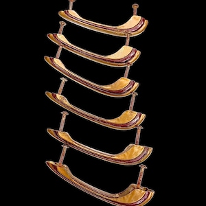 May include: A vertical arrangement of six wooden cabinet handles. Each handle is a light wood color with a dark red stripe and is attached with a nail. The background is solid black.