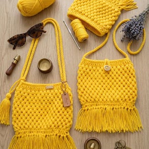 May include: Two bright yellow crocheted bags with long fringe, a matching ball of yarn, a crochet hook, a small metal container, a brown wooden tool, and dark tortoiseshell sunglasses. The bags feature a textured popcorn stitch and a single button.