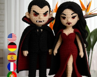 May include: Two crocheted vampire dolls, a male and a female, stand side-by-side. The male doll wears a black suit with a red-lined cape. The female doll is in a red dress and black cape. The text "PDF Patterns" is at the top.