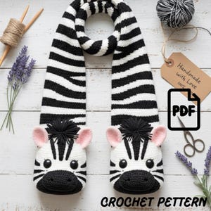 May include: A handmade crochet zebra scarf with black and white stripes. The scarf features zebra heads with pink ears and black manes at each end. The text "CROCHET PATTERN" is at the bottom of the image.