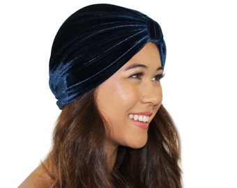 May include: A dark blue velvet turban hat. The hat is folded and gathered to create a soft, drapey look.