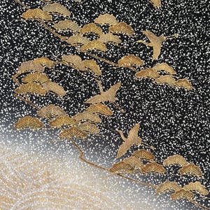 May include: A black fabric textile featuring a white speckled pattern, gold-colored pine tree motifs, and flying crane silhouettes. The lower section transitions into a gradient of white and gold with fine, wavy line details across the surface.