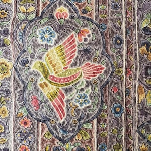 以下が含まれることがあります： 赤と黄色の翼を持つ鳥の模様が中央に配置された、花柄と葉柄のモチーフに囲まれた模様の生地のクローズアップ。背景は、茶色、紫、緑の垂直ストライプに花のアクセントが施されています。