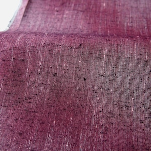 May include: Close-up of a textured fabric in a deep burgundy colour. The fabric has a woven appearance with subtle variations in tone and small flecks of darker colour throughout. The material is slightly folded, showing its texture and depth.
