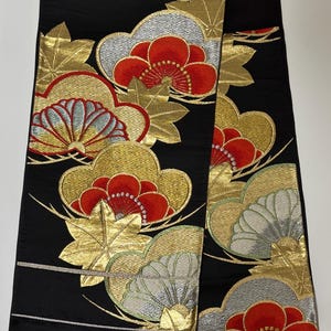 以下が含まれることがあります： 黒色の生地に、金、赤、銀色の花と雲のモチーフが施された装飾的なデザイン。 スタイリッシュな花と葉のデザインで、豊かで質感のある外観を作り出しています。 この生地は、伝統的な衣服に使用される可能性があります。