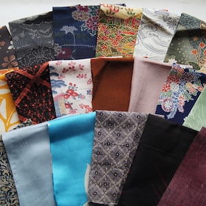 以下が含まれることがあります： 半円形に配置された、カラフルな生地の見本コレクション。生地は、茶色、青、黄色、緑の色合いで、花柄、幾何学模様、抽象的なデザインなど、さまざまなパターンを表示しています。見本はさまざまな素材で作られています。