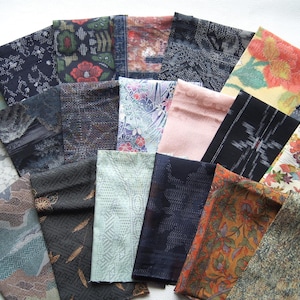 以下が含まれることがあります： さまざまな色と模様の、折りたたまれた布の正方形のコレクション。 青、緑、赤、茶色の色合いで、花柄、幾何学模様、抽象的なデザインが施されています。 さまざまなテクスチャとスタイルが並んでいます。