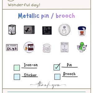 Puede incluir: Imagen que muestra varios pines y broches metálicos con diseños originales. Los diseños incluyen una máquina de garras, un dinosaurio en un televisor, figuras de palo y texto humorístico. También incluye el texto "Wonderful day!" y "Thank you."