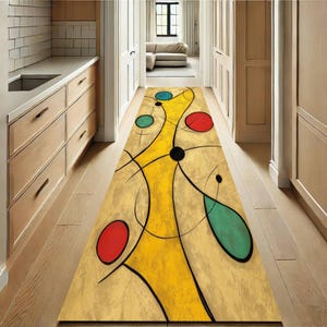 May include: A long, rectangular abstract rug with a yellow central design and colorful circles. The rug features a beige background with red, blue, and green circular shapes, and black lines. The rug is placed in a hallway with wooden floors.