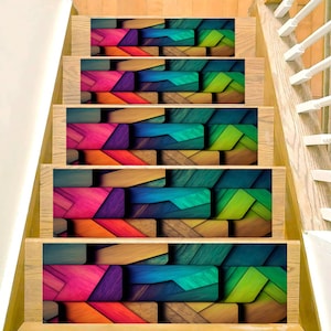 Könnte beinhalten: Treppe mit dekorativen Stufen. Die Stufen zeigen ein farbenfrohes, geometrisches Muster aus geschichteten Rechtecken in Rosa, Orange, Lila, Blau, Grün und Braun. Die Treppe hat einen Holzrahmen und ein weißes Geländer.