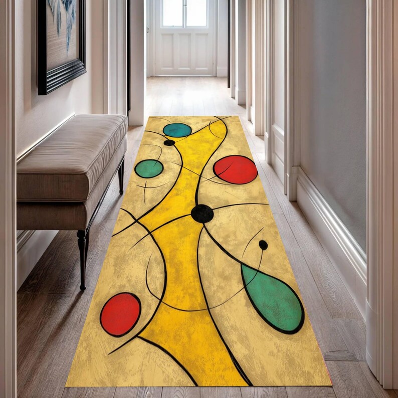 May include: A rectangular hallway runner rug with an abstract design. The rug features a yellow central shape with black lines and colorful circles in red, teal, and blue. The rug is placed on a wooden floor in a hallway.