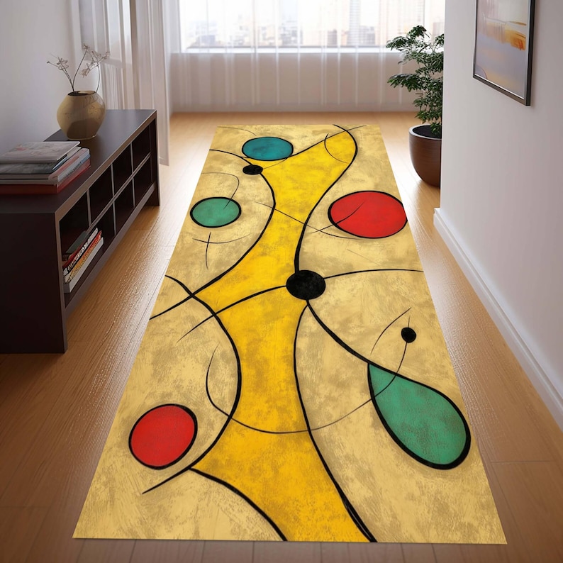 May include: Abstract art runner rug with a beige background, featuring a yellow central design with black lines and colorful circles in red, teal, and green. The rug is rectangular and placed on a wooden floor.