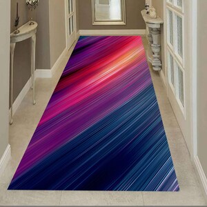 May include: A long rectangular runner rug featuring a vibrant abstract pattern of diagonal lines in shades of deep blue, purple, magenta, and bright orange, creating a dynamic gradient effect across the entire surface of the floor covering.