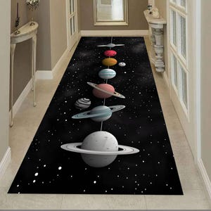 Puede incluir: Una alfombra negra para pasillo con diseño espacial. La alfombra muestra una serie de planetas con anillos sobre un fondo estrellado. Los planetas son de varios colores, incluyendo blanco, azul, rosa y naranja. Ideal para un pasillo.
