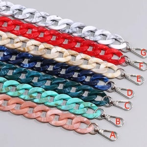 May include: Seven acrylic chain bag straps in various colors including white marble, red, beige, dark blue, dark green, light turquoise, and light pink. Each strap features silver-toned metal lobster claw clasps labeled with letters A through G.