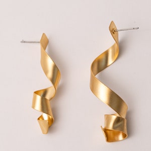 a pair of gold - plated metal earrings on a white background