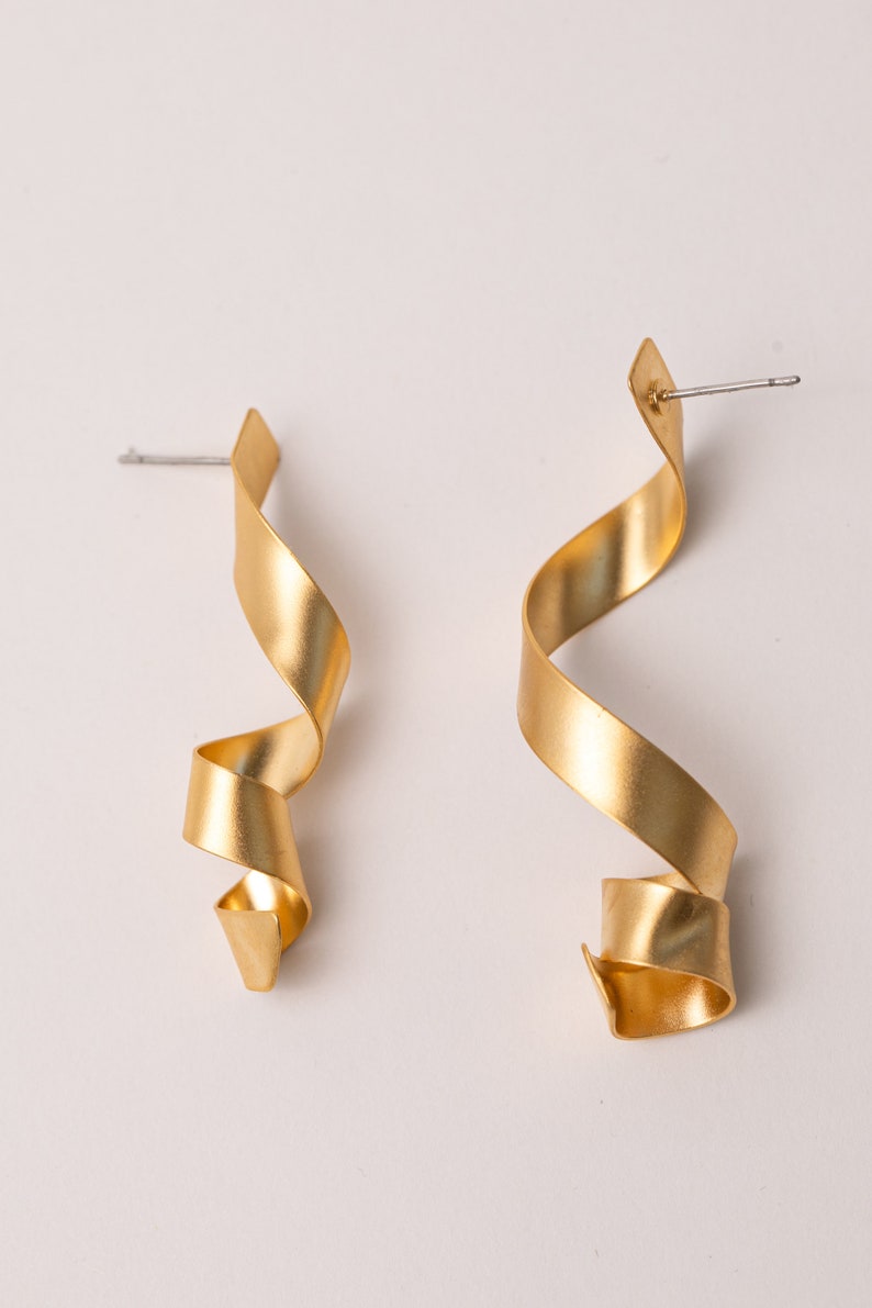 a pair of gold - plated metal earrings on a white background
