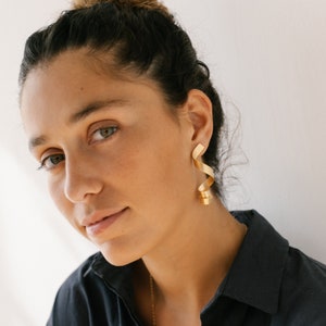 a woman wearing a black shirt and gold earrings