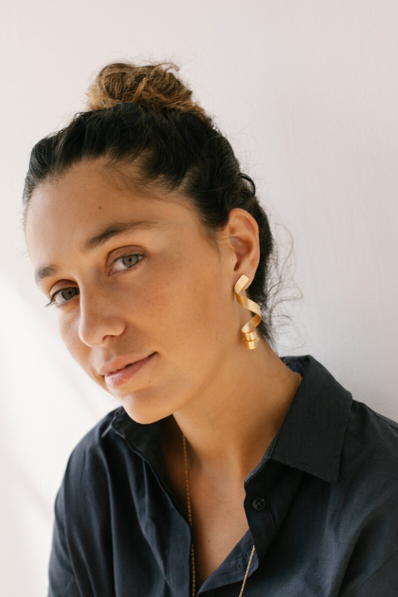 a woman wearing a black shirt and gold earrings