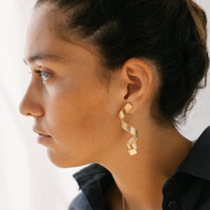 a woman wearing a black shirt and gold earrings