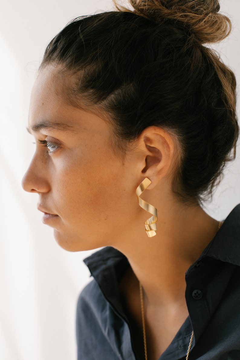 a woman wearing a black shirt and gold earrings