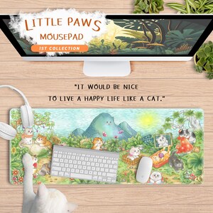 May include: A Little Paws mousepad with a whimsical cat-themed design. The mousepad features a landscape with cartoon cats, mountains, and the text "IT WOULD BE NICE TO LIVE A HAPPY LIFE LIKE A CAT." The words "LITTLE PAWS MOUSEPAD 1ST COLLECTION" are also visible.