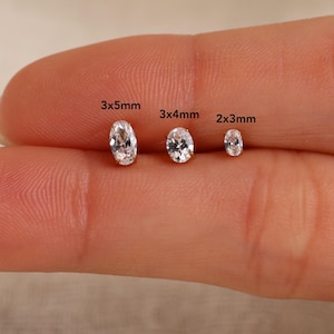 Op de afbeelding: Drie heldere, ovaal geslepen edelstenen op een rij, gelabeld met hun respectievelijke afmetingen van 3x5mm, 3x4mm en 2x3mm. Elke steen heeft een gefacetteerd oppervlak dat licht reflecteert, wat zorgt voor een briljante en transparante uitstraling.