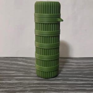 May include: A green cylindrical container with a ribbed texture and a hinged lid.