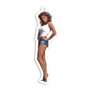 Pode incluir: Uma mulher vestindo um top branco sem mangas e shorts jeans azuis com um remendo que diz "Select-A-Action".