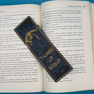 Rocky alien bookmark with a golden mechanical arm giving thumbs up on a blue background, Project Hail Mary inspired, sci fi. THUMBS UP BABY