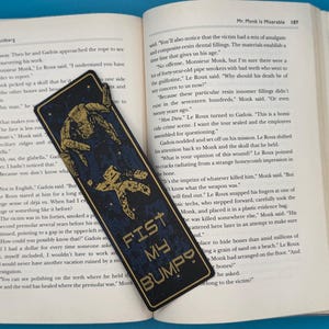 Rocky alien bookmark with a gold mechanical silhouette on black, sci-fi/gamer gift inspired by Project Hail Mary. FIST MY BUMP