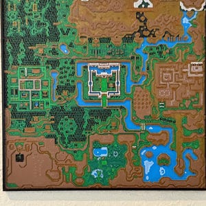 May include: A detailed, colorful map of a fantasy world, featuring green forests, brown mountains, blue rivers, and a central white structure. The map is framed in black, with a textured appearance, reminiscent of a video game.