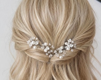 May include: Blonde hair styled in a half-up, half-down hairstyle, adorned with delicate floral hairpins. The hairpins feature clusters of small white pearls and clear crystals, adding a touch of elegance to the look. The hair has soft waves.