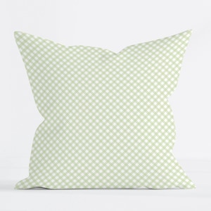 May include: A square throw pillow featuring a light sage green and white gingham check pattern. The fabric displays a consistent diagonal grid design across the entire surface of the cushion, which maintains a soft, plump, and uniform square shape.