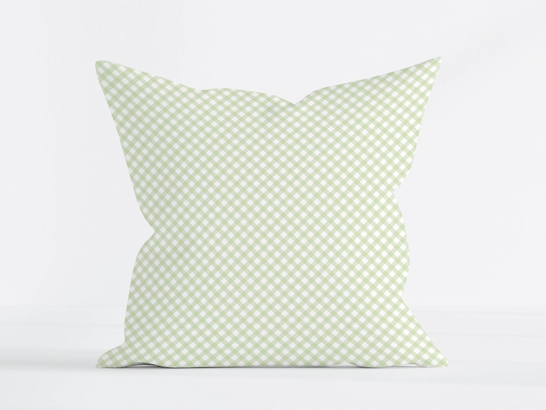 May include: A square throw pillow featuring a light sage green and white gingham check pattern. The fabric displays a consistent diagonal grid design across the entire surface of the cushion, which maintains a soft, plump, and uniform square shape.