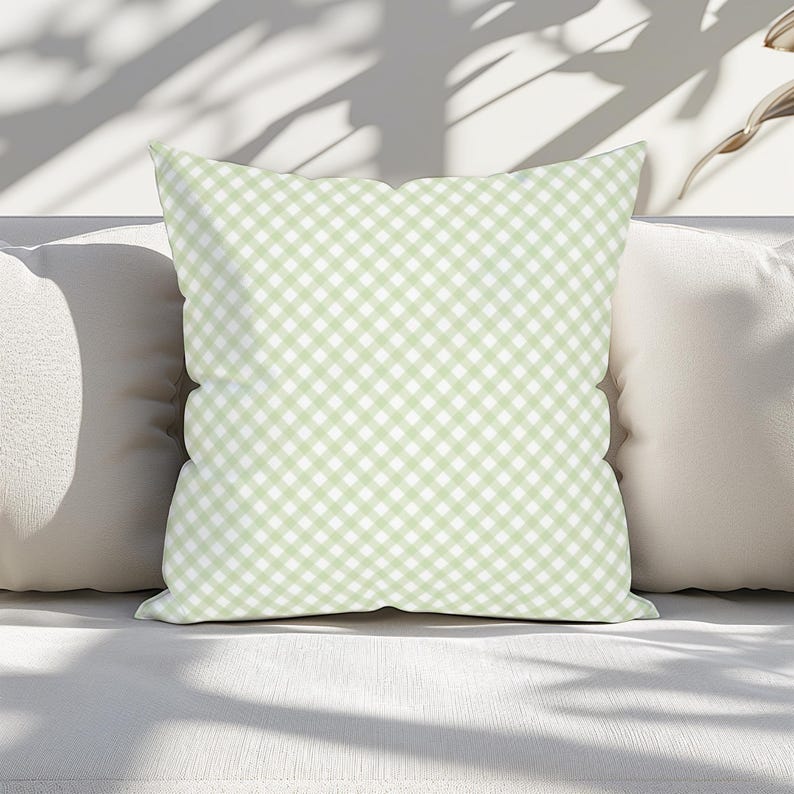 May include: A square throw pillow featuring a light sage green and white gingham check pattern. The fabric displays a consistent diagonal grid design across the entire surface of the cushion, creating a uniform and repeating checkered appearance.