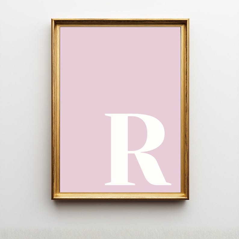 Pode incluir: Uma impress&atilde;o de arte emoldurada com um fundo rosa claro s&oacute;lido e uma letra R mai&uacute;scula grande, branca e em negrito centralizada no quadrante inferior direito. A obra est&aacute; contida numa moldura retangular fina de tom dourado met&aacute;lico.