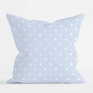 May include: A square throw pillow featuring a light blue fabric base with a repeating pattern of small, evenly spaced white polka dots. The pillow has a soft, plush appearance with slightly rounded corners and a consistent, uniform design.