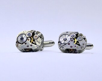 May include: A pair of silver cufflinks with intricate clockwork designs. The cufflinks feature exposed gears and a small silver dial with the text "Swiss Made".