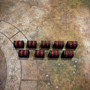 May include: Twelve black and red numbered counters, each with a different number from 1 to 12. The counters are arranged in a semi-circle on a brown and green surface.