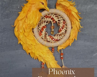 May include: A handcrafted dreamcatcher with a phoenix design. The dreamcatcher features a circular woven center with orange and brown beads, surrounded by a frame and wings in shades of yellow and orange. The text "Phoenix Dreamcatcher" is at the bottom.