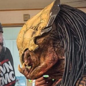 Könnte beinhalten: Detaillierte Predator-Maske in Beige- und Brauntönen mit aufwendigen Texturen und langen schwarzen Dreadlocks. Die Person im Bild trägt ein schwarzes T-Shirt mit dem Text "RVN DMC".